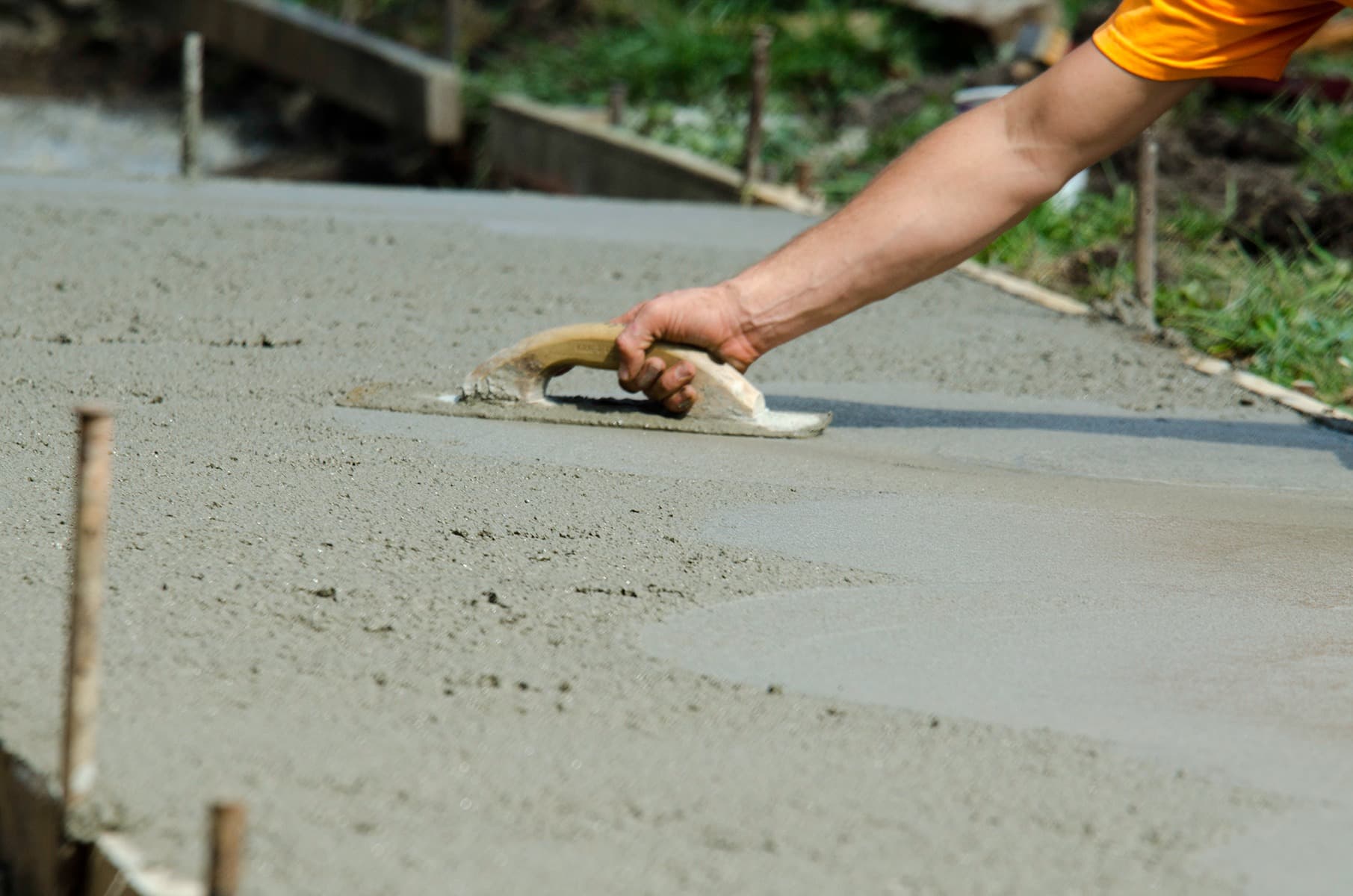 a-man-smoothing-the-wet-concrete-surface-of-a-path